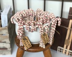 there are many candy canes in a white bowl on a stand with tags around it