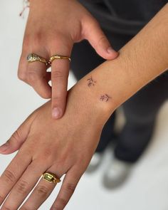 two people holding each other's hands with small tattoos on their wrist and fingers