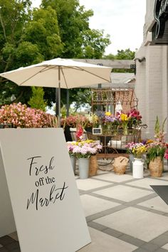 a sign that says fresh off the market in front of some potted plants and flowers