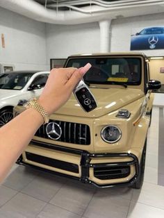 a hand holding a remote control in front of a mercedes truck at a dealership