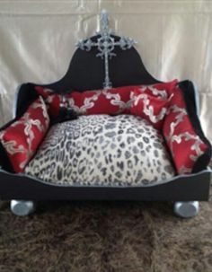 a black dog bed with red and white pillows on the bottom, an animal print pillow in the middle