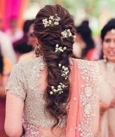 a woman in a bridal gown with flowers in her hair and another woman standing behind her