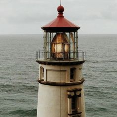 a light house sitting on top of a body of water next to the ocean in front of an overcast sky