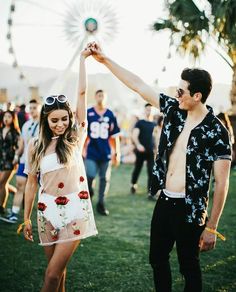 a man and woman holding hands in front of a crowd at an outdoor concert or festival