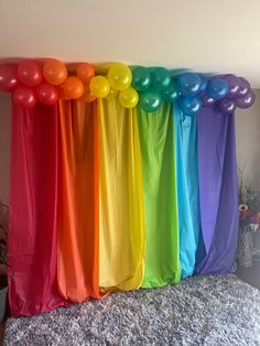 there are balloons and streamers in front of the rainbow colored curtain on the bed