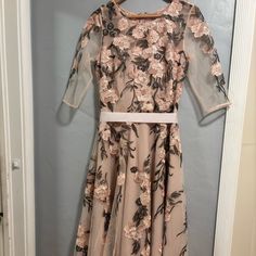 a dress hanging on a hanger in front of a door with a flower pattern