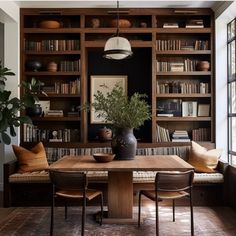 a living room filled with lots of bookshelves next to a table and chairs