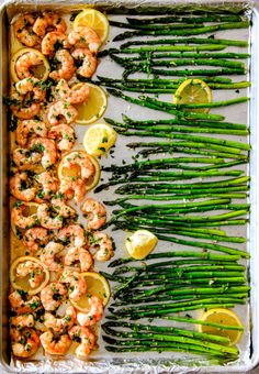 shrimp, asparagus and lemons on a sheet of baking tin with garnishes