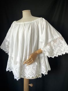 It is a rare piece of religious fashion circa 1930s.  This fabulous piece is a choir blouse made of cotton. Exquisite lace trim with cross pattern. Loose fit.  Round neckline with some hand sewing. Condition: There are some minor discrepancies due to age, including a small brownish stain on the sleeve that will probably come out once it is soaked.  Fantastic prop. SIZE: It will fit 14-18UK female  M/L male  Pit to pit: 46" flat  Length (hem of the neckline to bottom hem): 55cm/22" Trim: 7" Cotton Peasant Top With Lace Trim For Daywear, Victorian White Cotton Top, Victorian Style White Cotton Top, White Cotton Blouse With Crochet Trim, Broderie Anglaise Cotton Lace Tops For Daywear, White Peasant Top With Lace Trim, White Victorian Style Top With Lace Work, Bohemian Broderie Anglaise Tops For Daywear, Victorian Cotton Tops For Summer