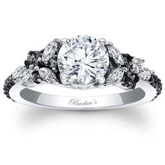 an engagement ring with black and white diamonds on the band, set in 18k white gold