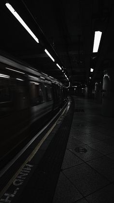 the train is moving through the dark subway station with its lights on and it's motion blurry