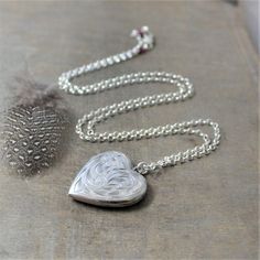 This sterling silver locket is beautifully engraved with a floral swirling plume design on the front; the reverse has been engraved from the previous owner "Elaine 1973 Love, Mom and Dad".  The heart shaped locket opens revealing two compartments awaiting your treasured photos.  The pendant is suspended from a  new sterling silver chain accented with tiny ruby rondelles (July birthstone) at the lobster clasp closure.Locket 30x22mmNecklace 24" (61cm)✤Our entire selection of lockets can be found h Ruby Locket, Present Picture, Silver Heart Locket, Push Present, Picture Locket, Sterling Silver Locket, Photo Locket Necklace, Silver Locket, Photo Locket