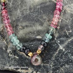 This handmade gemstone necklace is a true work of art, featuring a focal point of stunning watermelon tourmaline. The watermelon tourmaline, with its mesmerizing blend of pink and green hues, is beautifully showcased in a gold-finished jewelry wire setting, adding a touch of luxury and elegance to the piece. What makes this necklace truly unique is its chain, which is crafted from multi-colored tourmaline beads. These beads, in various shades of pink, green, and other colors, complement the wate Tourmaline Beads, Jewelry Wire, Watermelon Tourmaline, Shades Of Pink, Beaded Necklaces, Dainty Necklace, Gemstone Necklace, Wire Jewelry, Multi Colored