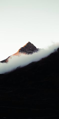 the top of a mountain is covered in clouds