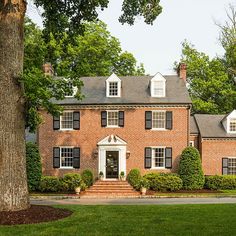 a large brick house surrounded by trees and grass