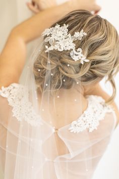 the back of a bride's head wearing a veil with flowers and pearls on it