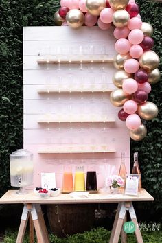 a table topped with lots of balloons next to a wooden shelf filled with bottles and glasses