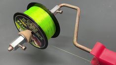 a spool of green fishing line being hooked up to a reel on a hook