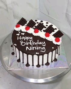 a chocolate birthday cake with white frosting and red cherries on top, sitting on a silver platter