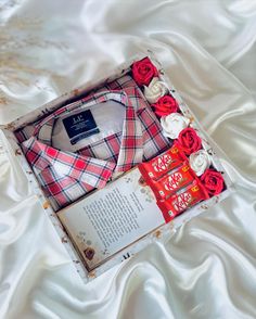 a red and white plaid shirt in a box with roses on the bottom, next to a card