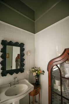 a bathroom with a sink, mirror and vase filled with flowers on the counter top