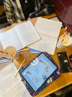 an open book sitting on top of a wooden table next to a cup of coffee