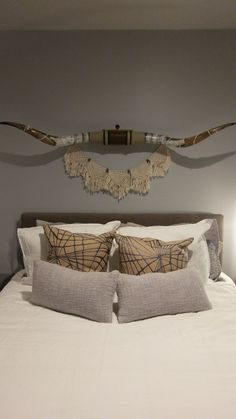 a bed with two pillows on top of it and a wall hanging above the headboard