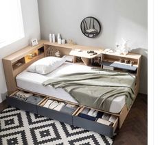 a bed with drawers underneath it and a rug on the floor in front of it