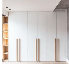 an empty room with white cupboards and wooden shelves