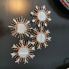 three sunburst shaped mirrors sitting on top of a black table next to a plate