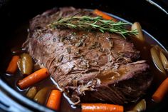 a pot roast with carrots and rosemary garnish in the slow cooker