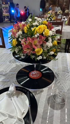 a table topped with an old record and flower centerpiece on top of a white table cloth