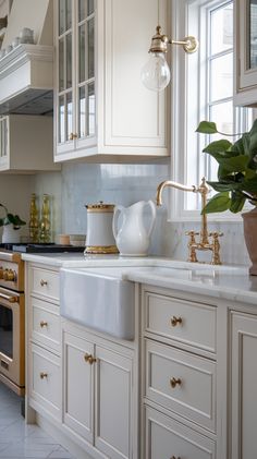 a kitchen with white cabinets and marble counter tops, gold faucets and brass accents