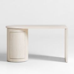 a white table sitting on top of a white floor next to a wooden cabinet in the shape of a door