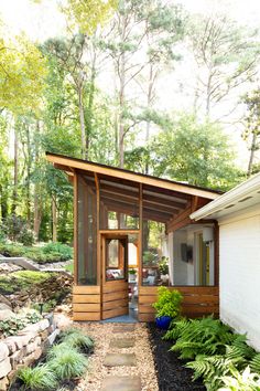 a small house in the middle of a wooded area with trees and shrubs around it