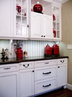 a kitchen with white cabinets and black counter tops