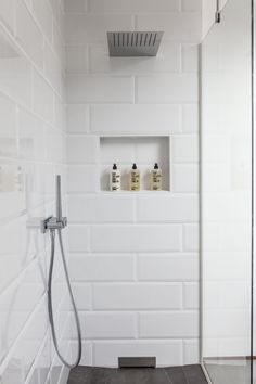 a white tiled shower with an open shelf above it