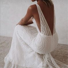 a woman in a white dress sitting on the floor with her back to the camera