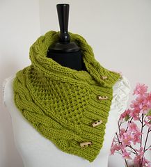 a green knitted cowl with buttons on the front and side, sitting on a mannequin