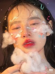 a woman with her face covered in white fluffy clouds and confetti around her eyes