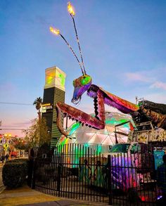 a large colorful alien statue sitting on top of a metal fence