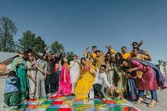 a group of people standing on top of a colorful blanket