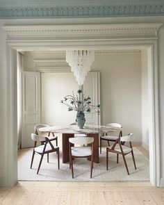 a dining room table with four chairs and a chandelier hanging from the ceiling