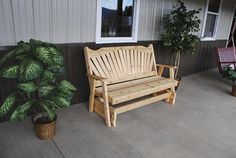 a wooden bench sitting in front of a window next to a potted green plant