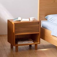 a small wooden nightstand sitting on top of a hard wood floor next to a bed