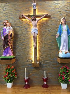 three crucifixs with flowers and candles in front of them