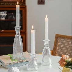 two candles sitting on top of a table next to a book