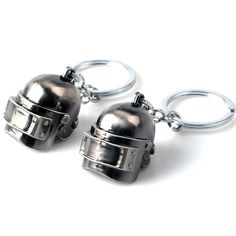 two metal key chains that are attached to each other, with helmets on the ends