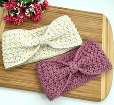 two crocheted headbands on a cutting board with flowers in the background