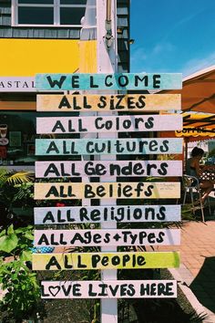 a wooden sign with many different types of signs attached to it's sides in front of a building